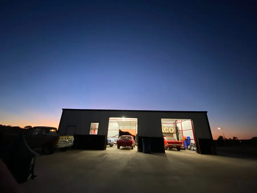 The shop at dusk with both bay doors open and lit